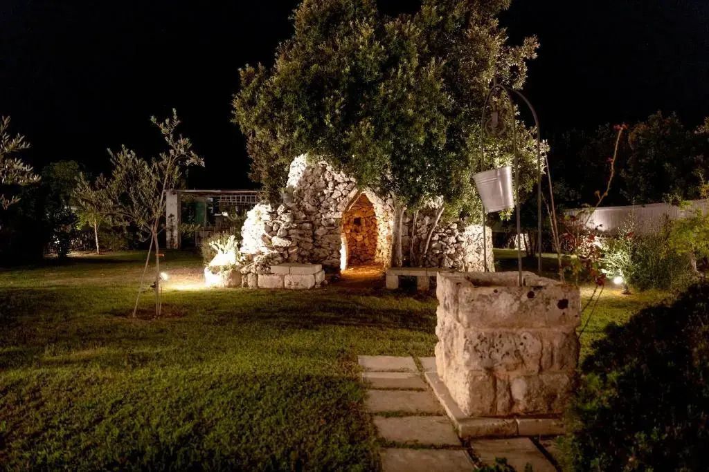 Romantisch beleuchtetes Gartenhaus aus Stein im Hotelgarten bei Nacht