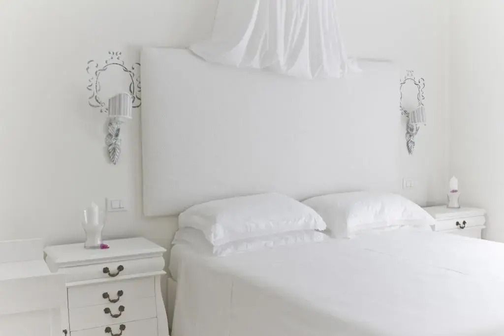 Minimalistisch eingerichtetes Schlafzimmer mit weißem Bettkopfteil und Nachttischlampen