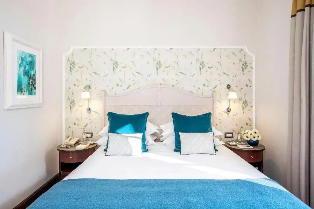 Elegantes Superior Doppelzimmer mit blauer Bettdecke und stilvoller Tapete