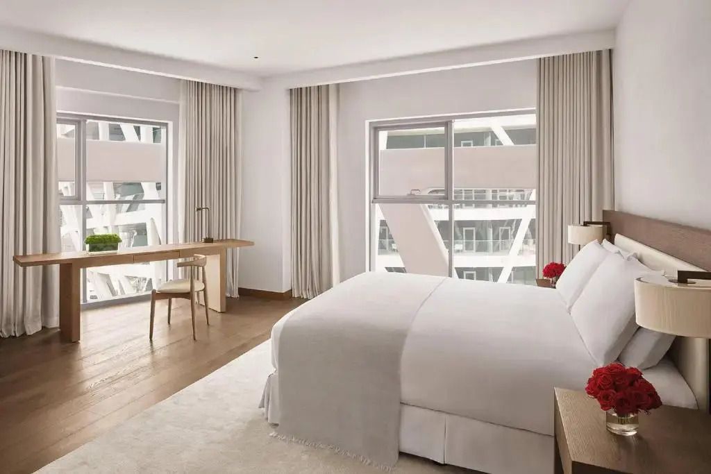 Modernes Schlafzimmer mit Kingsize-Bett und großen Fenstern mit Stadtansicht.