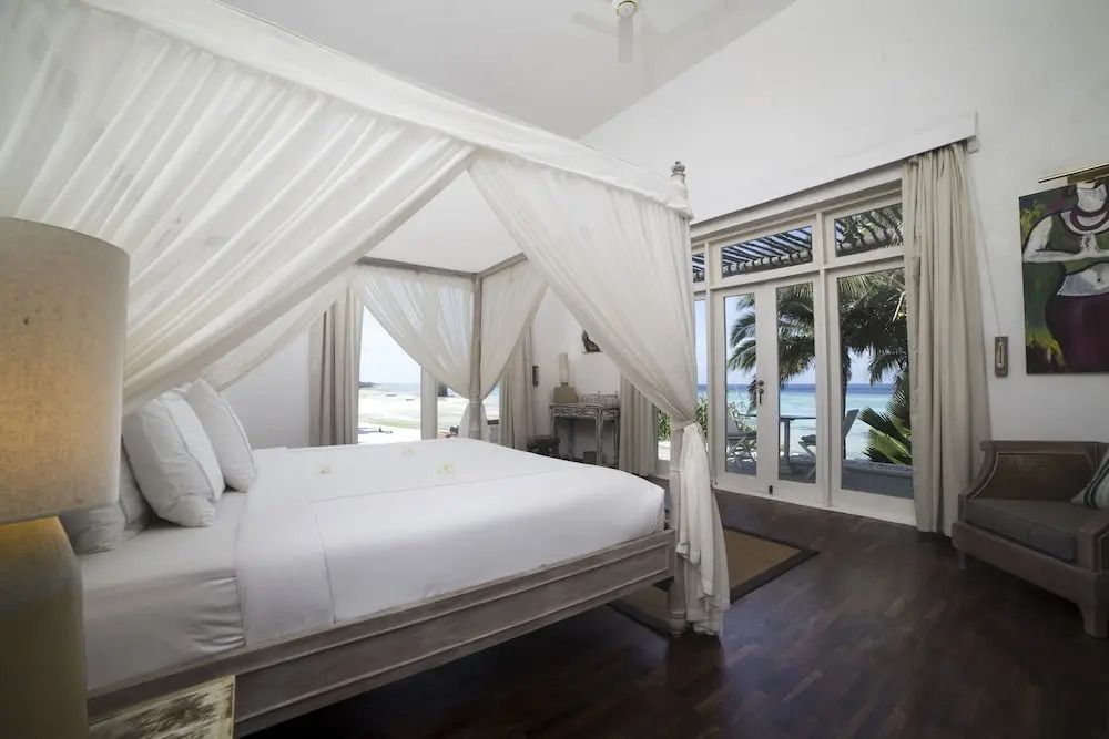 Elegantes Schlafzimmer mit Himmelbett und Meerblick durch große Fenster