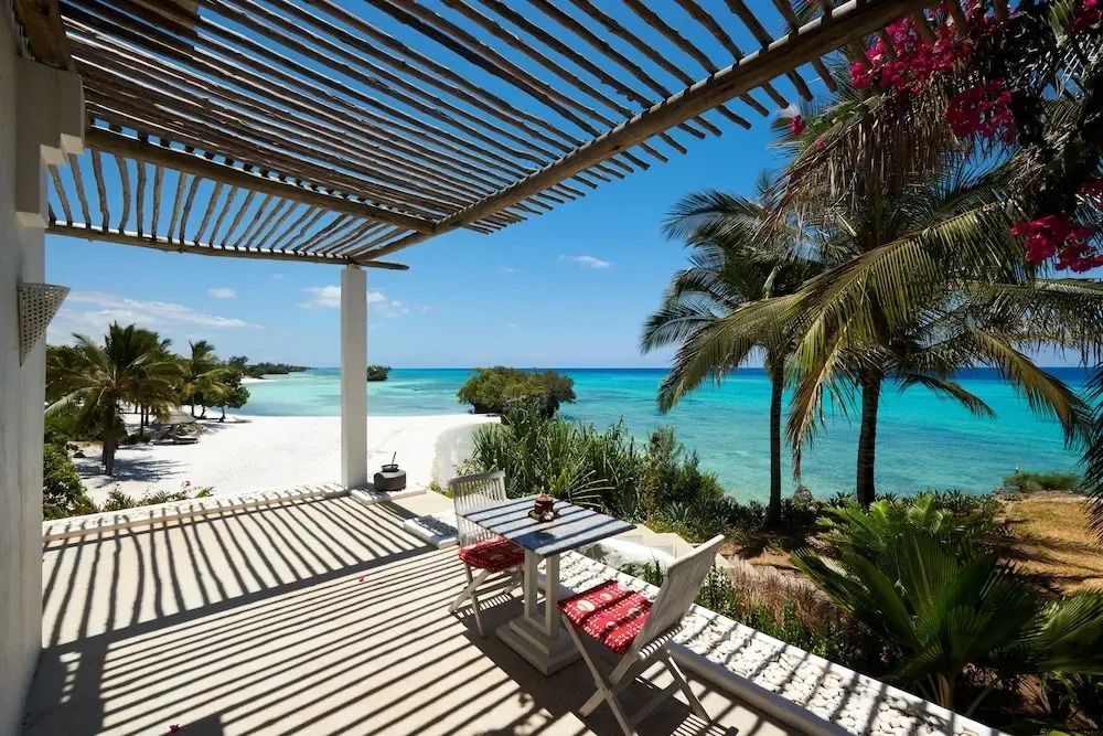Terrasse mit Blick auf das Meer und Palmen unter einer hölzernen Pergola
