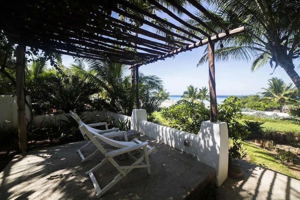 Private Terrasse mit Liegestühlen und Blick auf den tropischen Garten und das Meer