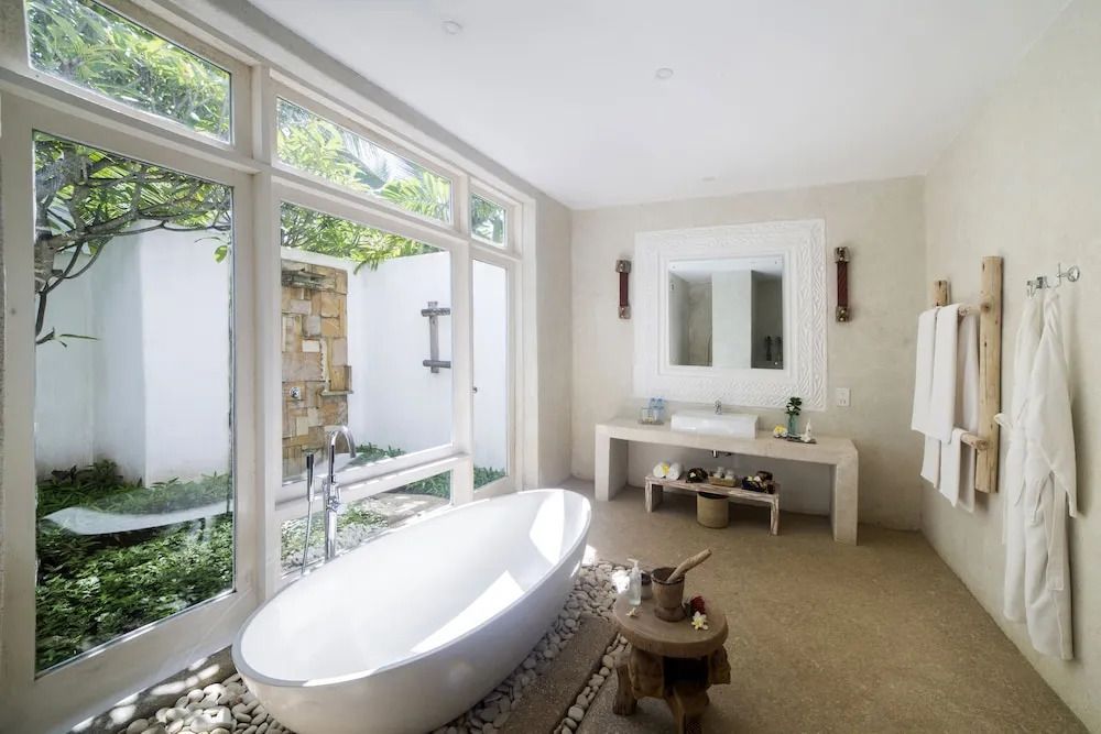Modernes Badezimmer mit freistehender Badewanne und großem Fenster zum Garten