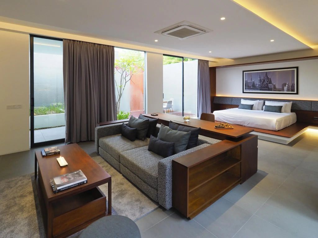 Elegante Suite mit modernem Design, großem Sofa und Doppelbett, Blick auf Balkon.
