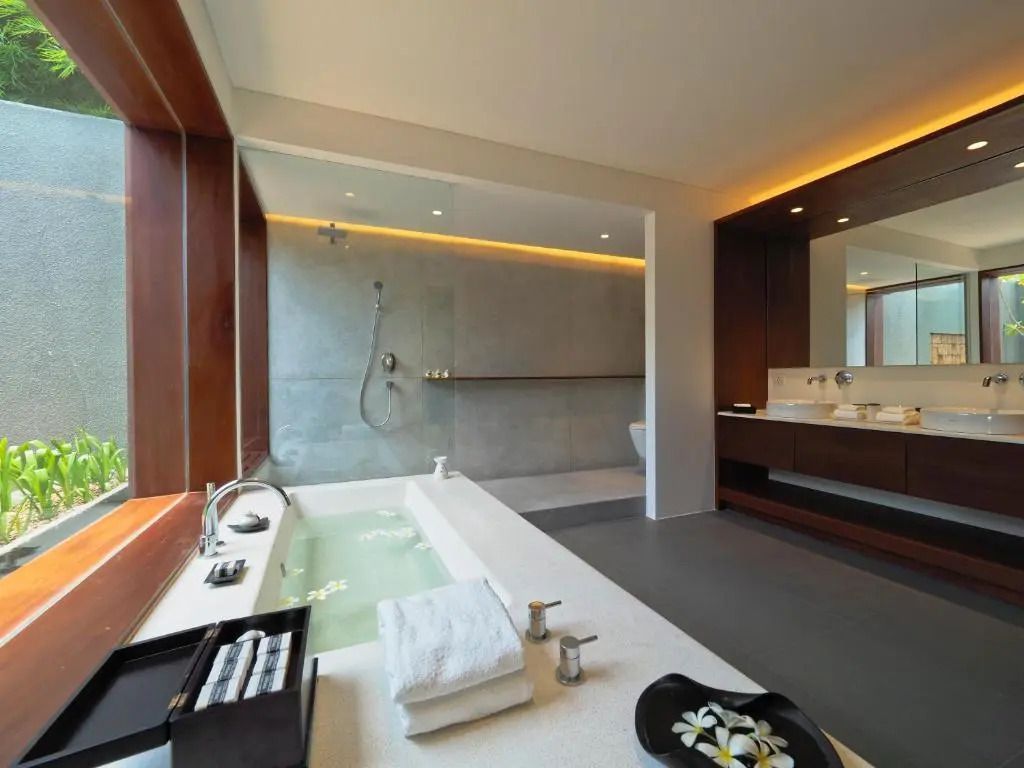 Luxuriöses Badezimmer mit großer Badewanne, Regendusche und stilvoller Beleuchtung.