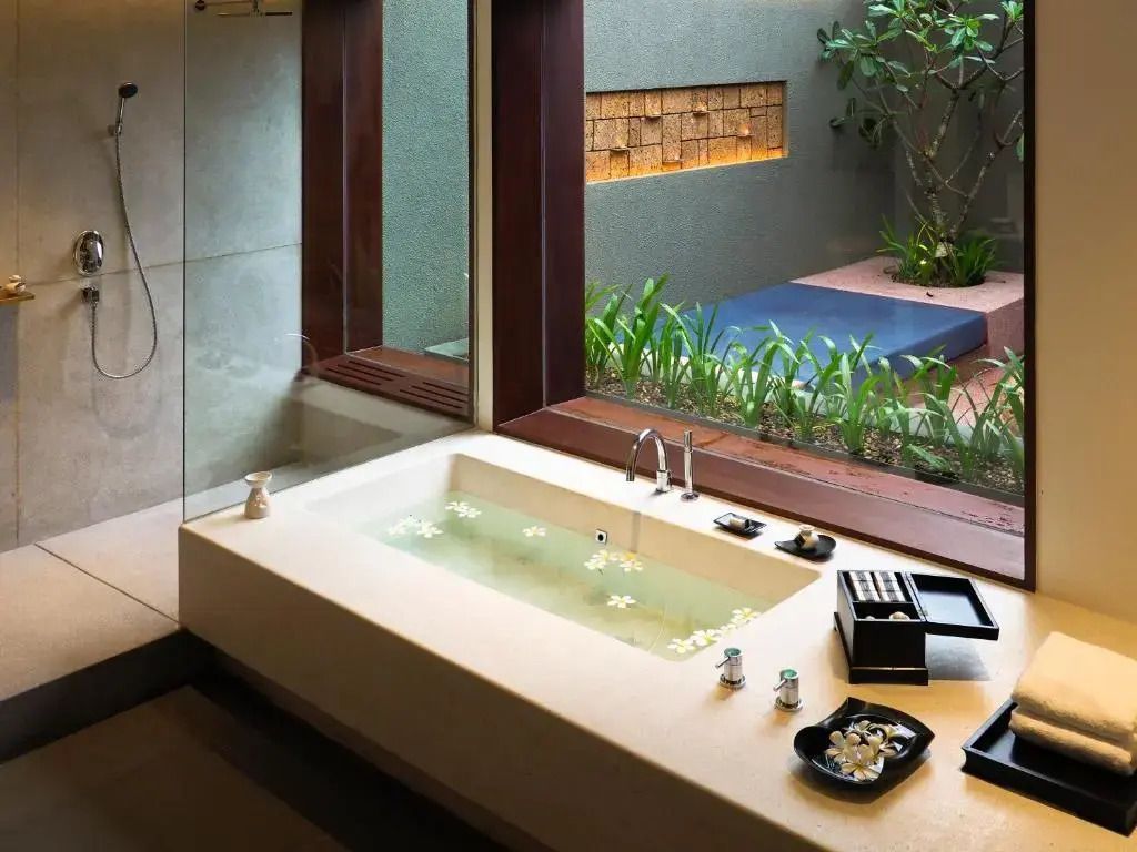 Helles Badezimmer mit eleganter Badewanne und Gartenblick, entspannende Atmosphäre.