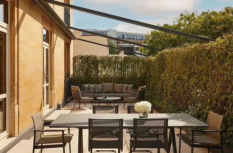 Private Terrasse mit Gartenmöbeln und grünem Sichtschutz
