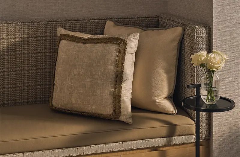 Luxuriöser Sessel mit dekorativen Kissen im beige und goldenen Ton im Hotelzimmer.