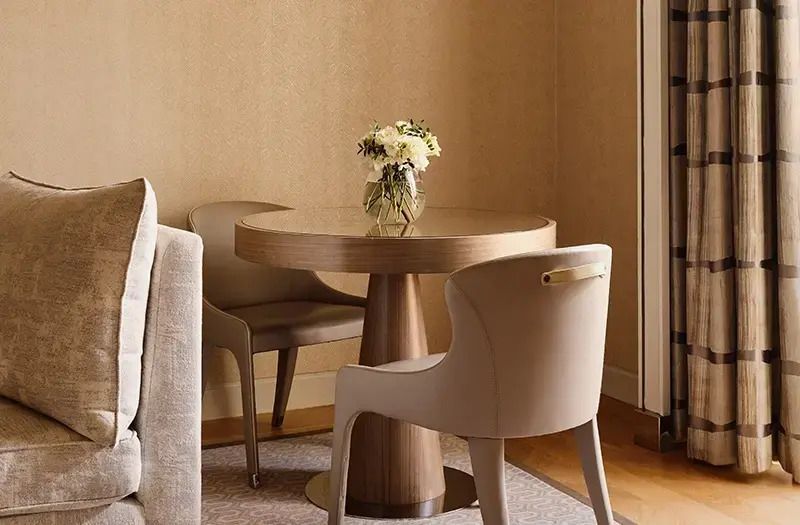 Runder Tisch mit Blumenarrangement und modernen Stühlen.