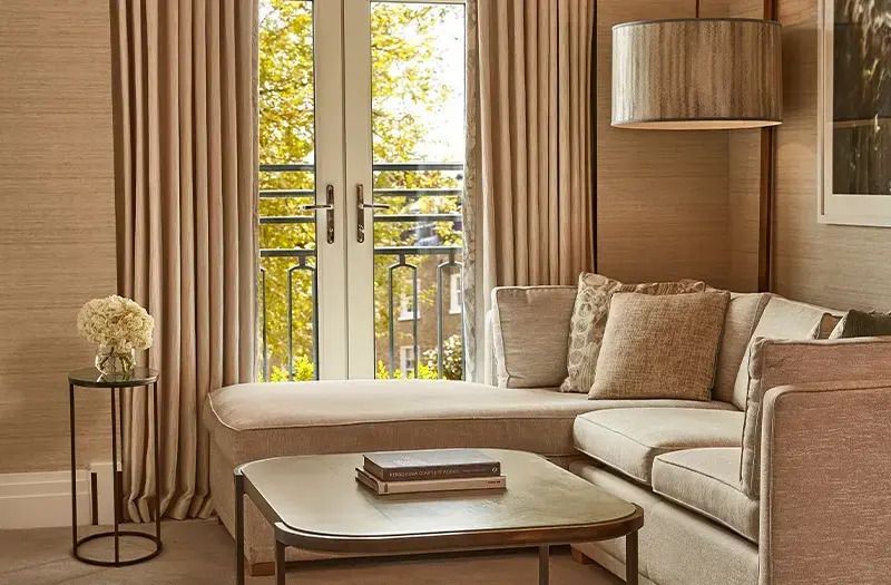 Gemütliche Sitzecke mit Sofa und Tisch vor bodentiefen Fenstern in der Junior-Suite.