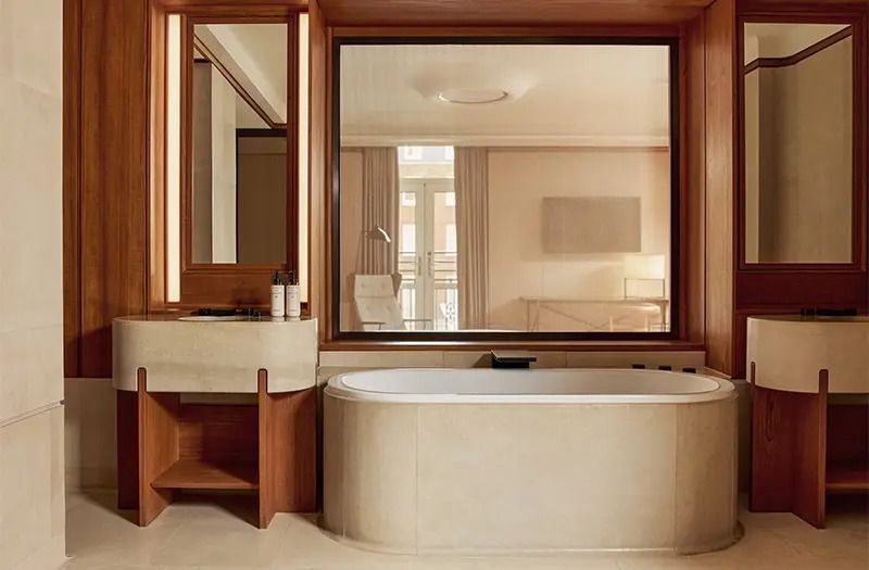 Luxuriöses Badezimmer mit freistehender Badewanne und großem Fenster in edlem Holzrahmen