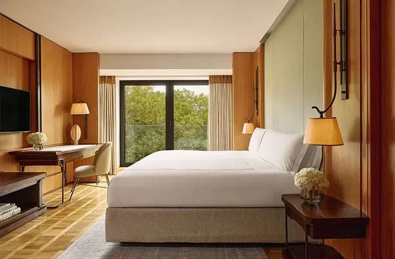 Geräumiges Schlafzimmer mit großem Bett und Aussicht auf Bäume durch große Fenster