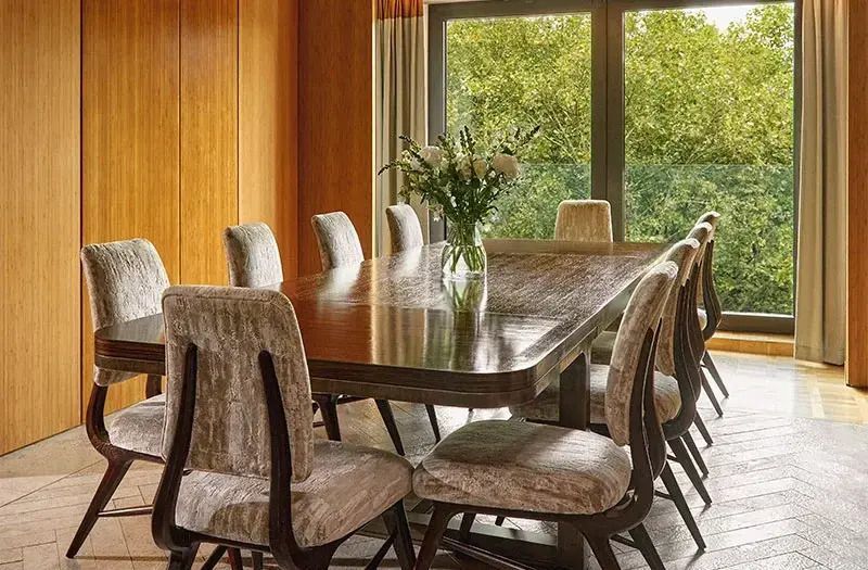 Stilvolles Esszimmer mit großem Holztisch und Stühlen vor Gartenblick