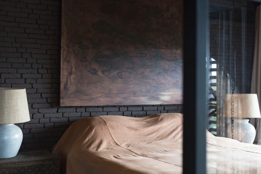 Elegantes Schlafzimmer mit Kunstwerk und gemauerten Wänden in warmen Erdtönen