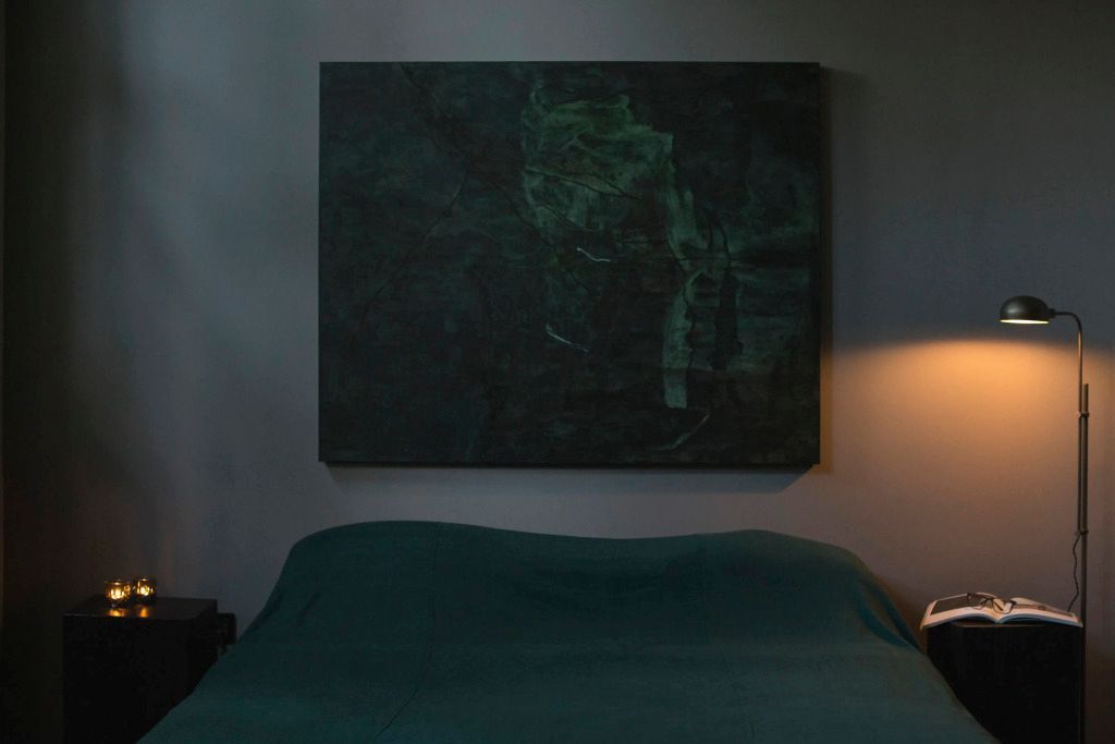 Schlafzimmer mit gedämpftem Licht und einem großen Kunstwerk an der Wand