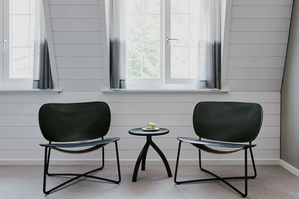 Sitzbereich mit zwei modernen schwarzen Sesseln und kleinem Tisch vor Fenster