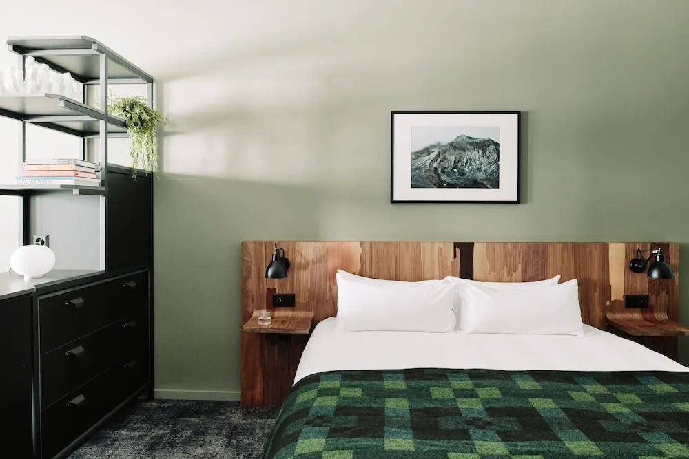 Gemütliches Bett in der Junior-Suite mit grünem Design und Kunstwerk