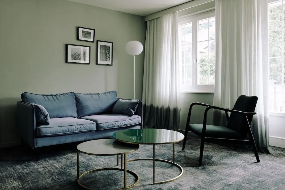 Elegantes Wohnzimmer mit blauer Couch und modernen Tischlampen im Hotelzimmer