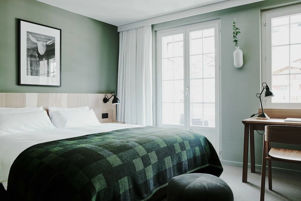 Gemütliches Bett im Zimmer mit weicher Decke und großem Fenster