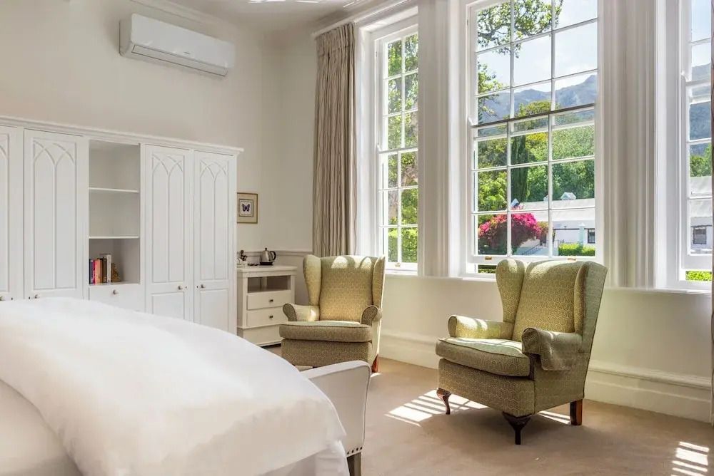 Helles Zimmer mit klassischen Sesselmöbeln und großem Fenster mit Gartenblick