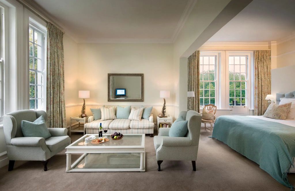 Helle Suite mit eleganter Sitzecke und großem Bett in modernen Pastellfarben