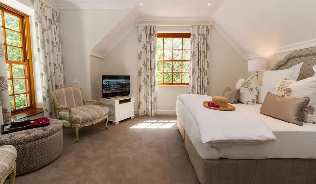 Helles Schlafzimmer mit Doppelbett elegantem Sessel Flachbildfernseher und Fenster.