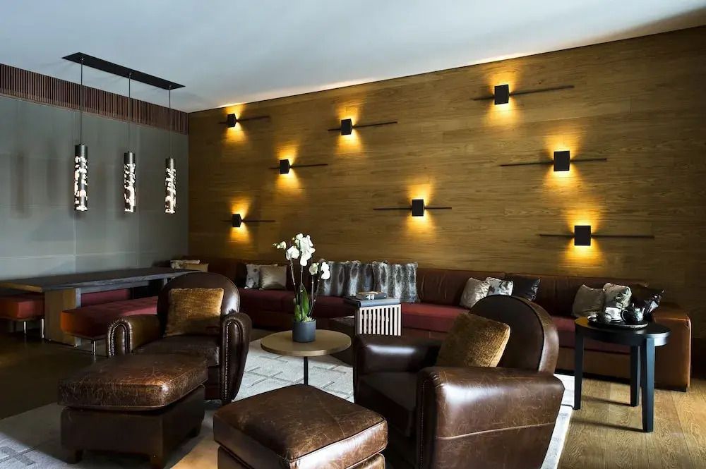 Elegante Lounge mit Lederstühlen, Holzwand und stimmungsvoller Beleuchtung