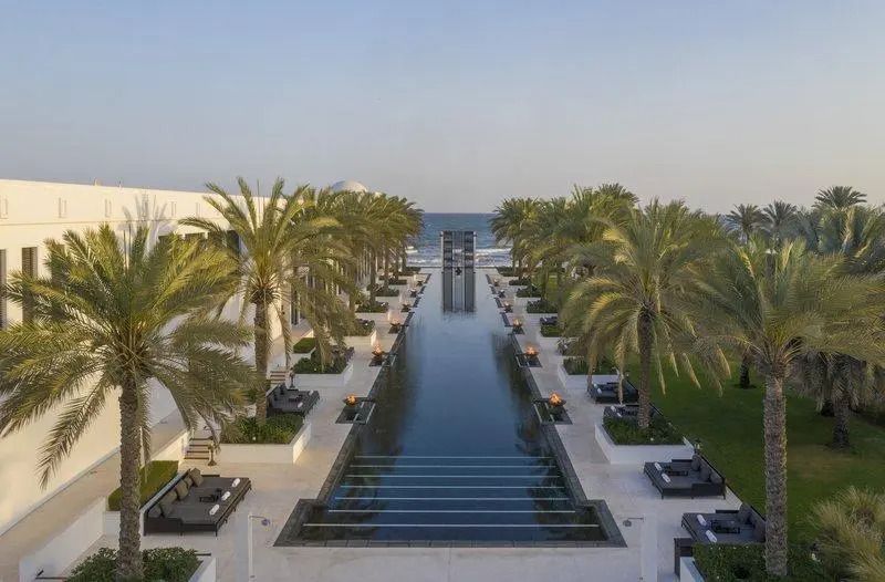 Luxuriöser Poolbereich mit Palmen und Meerblick im Hotel The Chedi Muscat