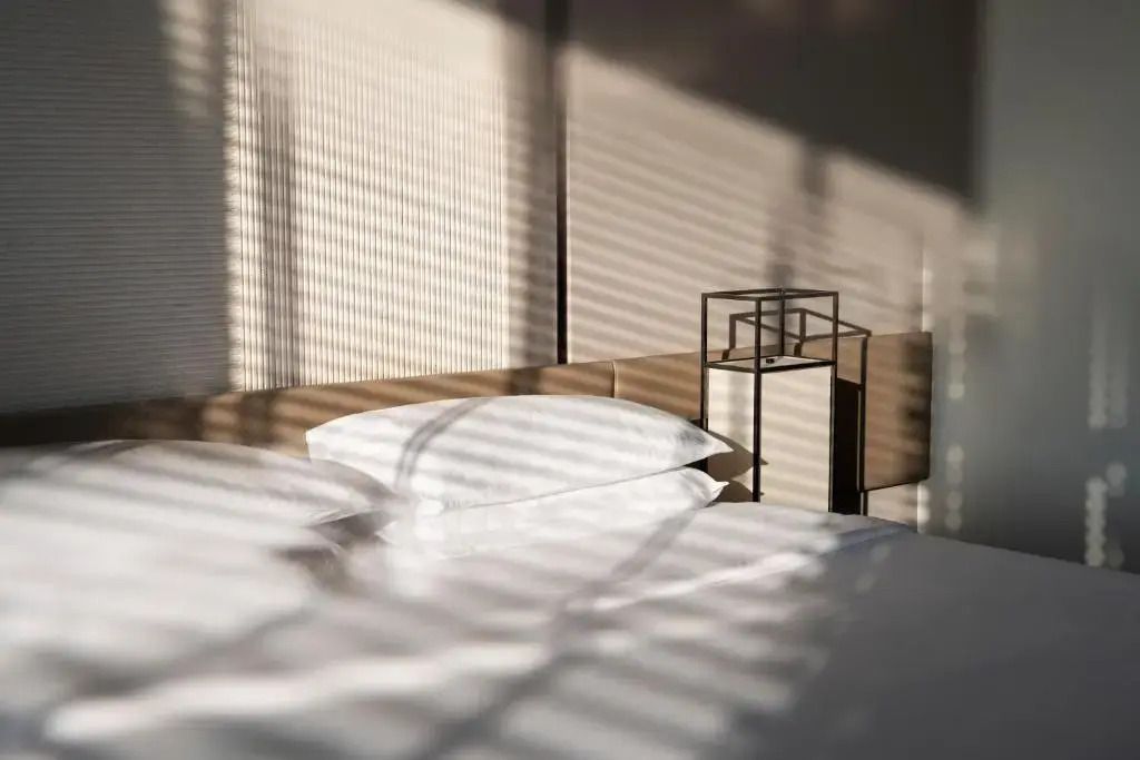 Sonnenlichtmuster auf Bett mit moderner Tischlampe