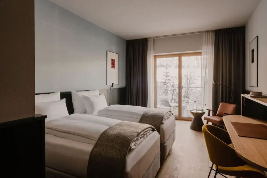 Modernes Doppelzimmer mit zwei Einzelbetten und Blick auf schneebedeckte Landschaft