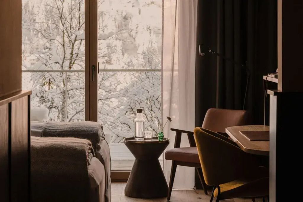 Sitzecke im Zimmer mit Blick auf winterliche Landschaft durch ein großes Fenster