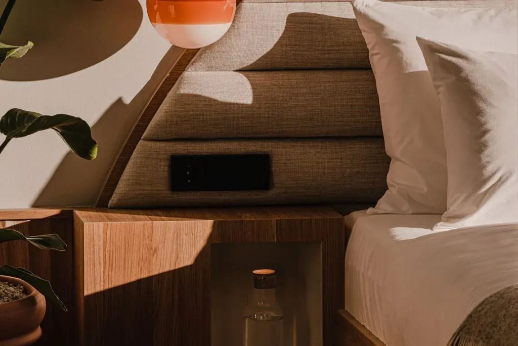 Nahaufnahme einer gemütlichen Bettseite mit Designer-Leuchte im Hotelzimmer
