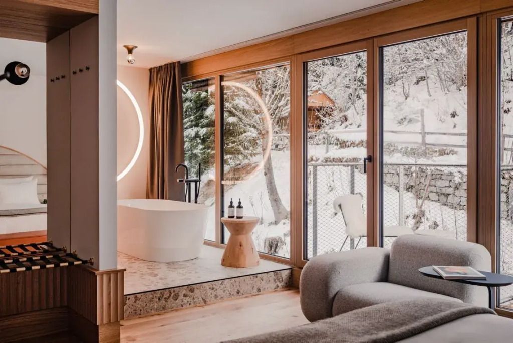 Modernes Badezimmer mit freistehender Badewanne und großem Fenster mit Schneeblick