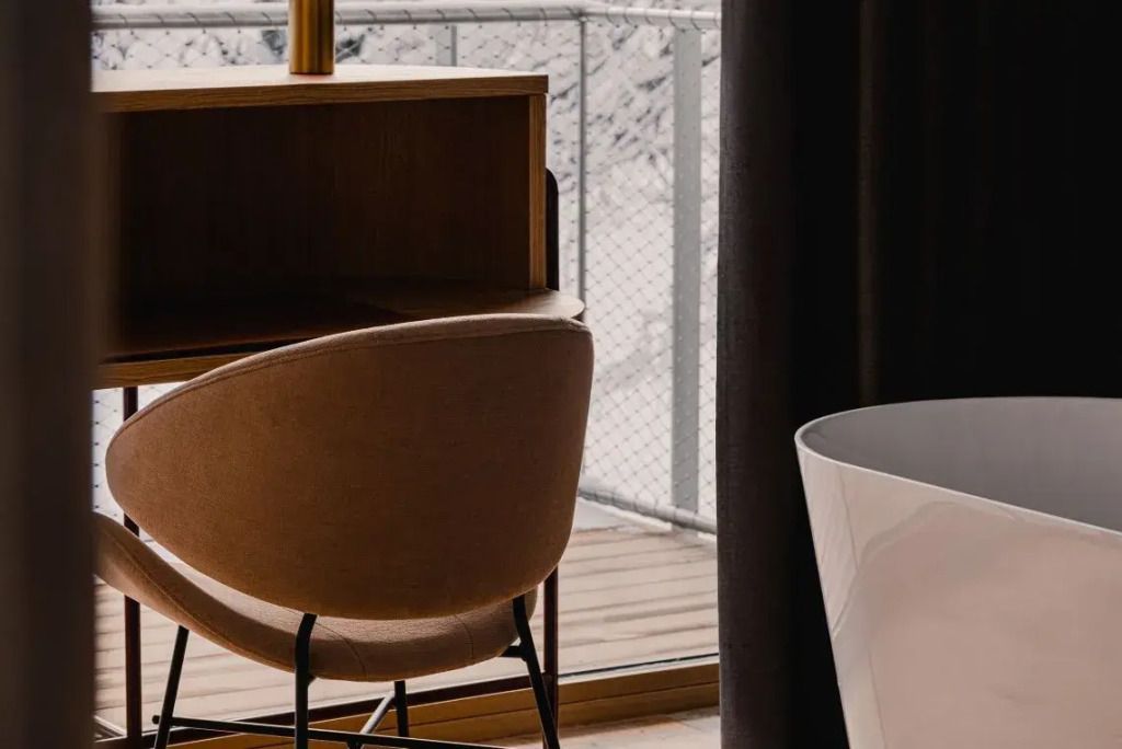 Arbeitsbereich in einer Suite mit Blick auf den Balkon und verschneite Landschaft