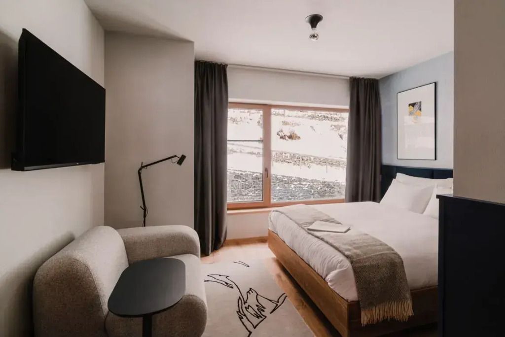 Helles Hotelzimmer mit Doppelbett, großem Fenster und stilvoller Einrichtung