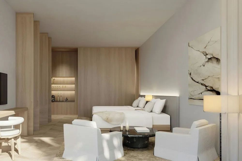 Luxuriöses Schlafzimmer in hellen Tönen mit elegantem Sitzbereich und hochwertigen Holzverkleidungen.