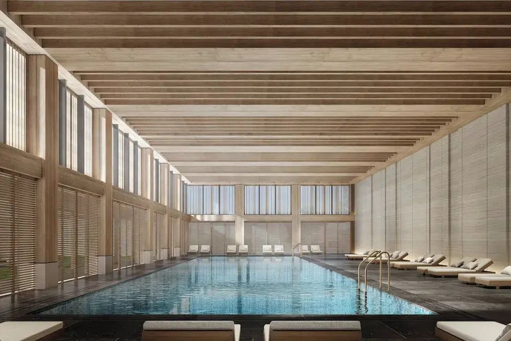 Großzügiger Indoor Pool im Hotel The Dali EDITION mit Holzdecke und stilvollen Liegen am Beckenrand.