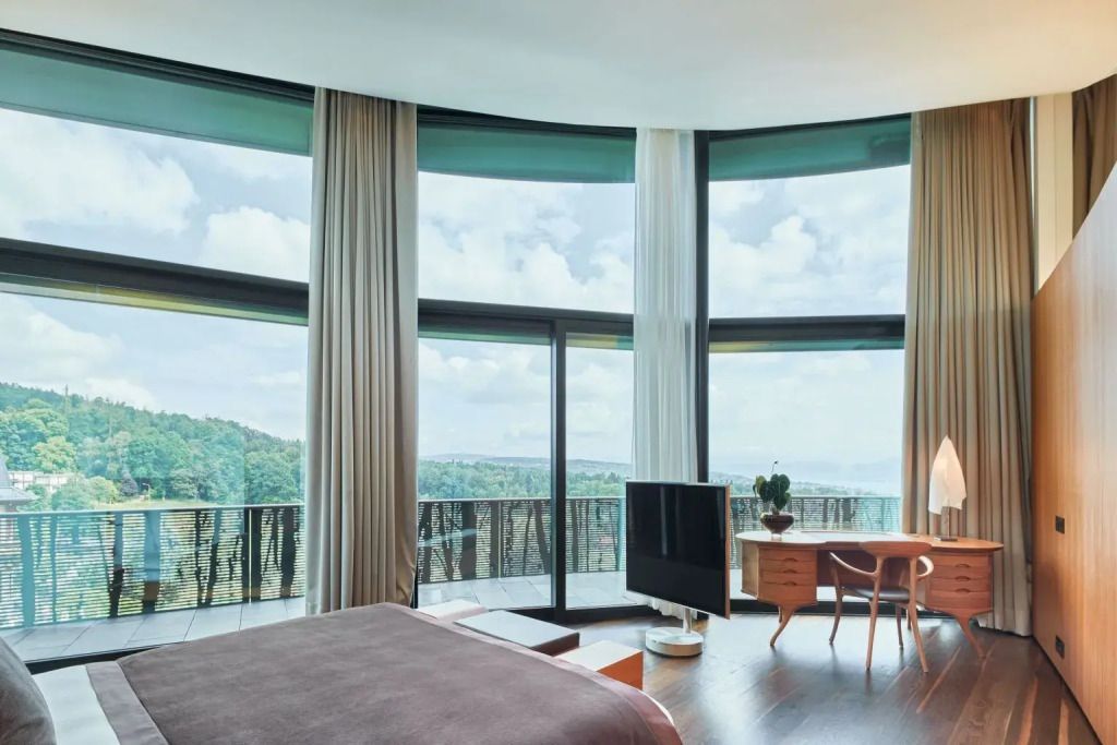 Weitläufige Fensterfront mit Blick in die grüne Landschaft und moderner Einrichtung