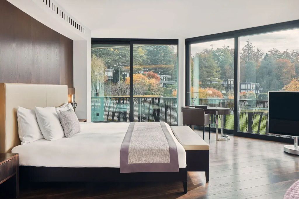 Helles Zimmer mit Doppelbett und großen Panoramafenstern mit Blick auf den Balkon
