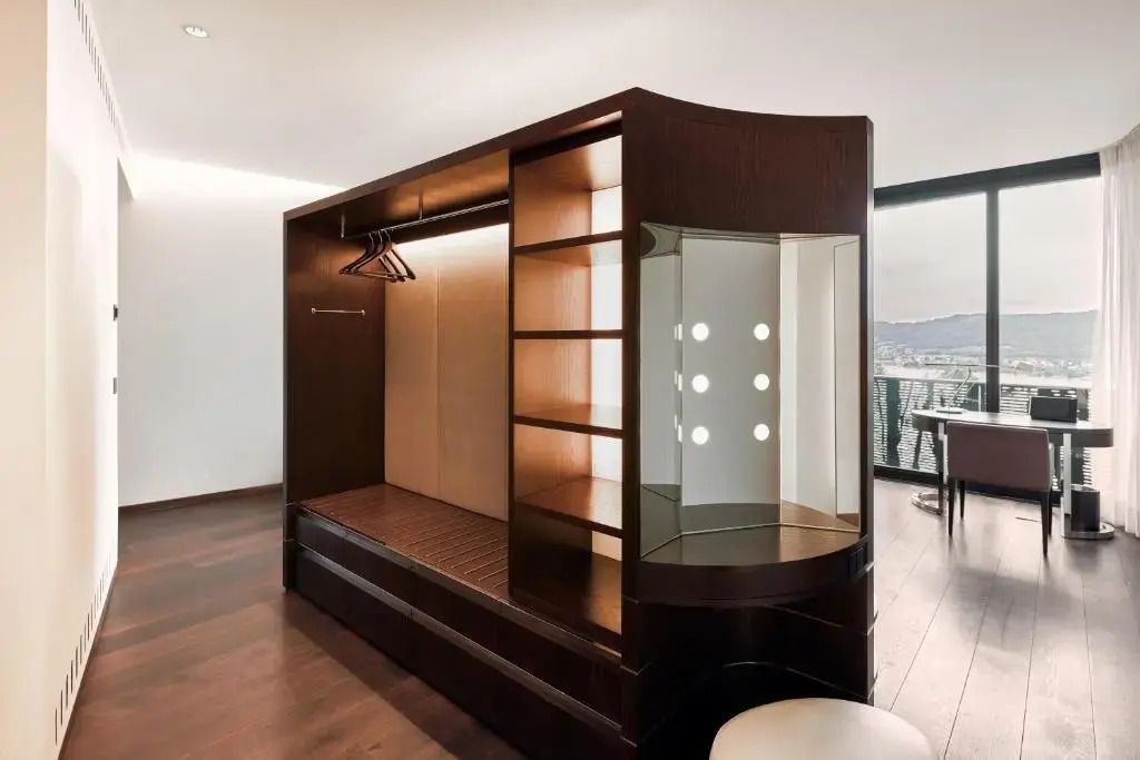 Offener Kleiderschrank im Deluxe Zimmer mit Spiegel- und Stauraumelementen.