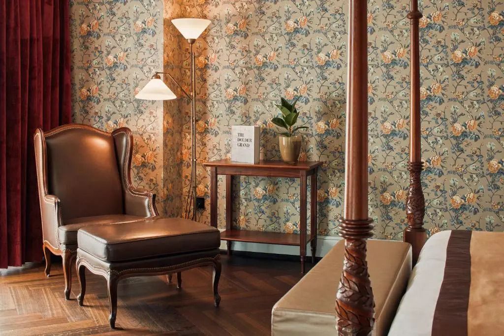 Lesesessel neben einem kleinen Tisch mit Lampe im stilvollen Schlafzimmer.