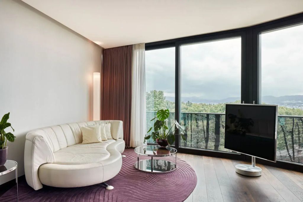 Wohnbereich mit runder Couch und raumhohen Fenstern