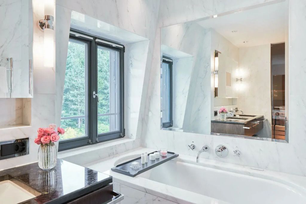 Großes Badezimmerfenster mit Marmorbadewanne und eleganten Details