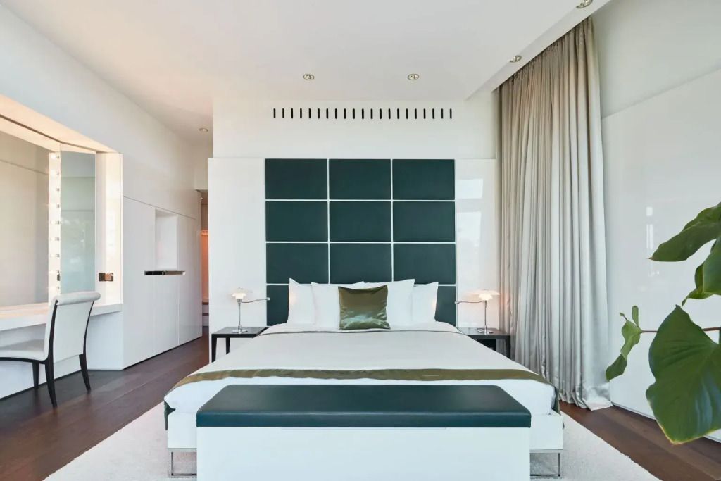 Luxuriöse Suite mit eleganter grüner Kopfwand und großzügigem Doppelbett
