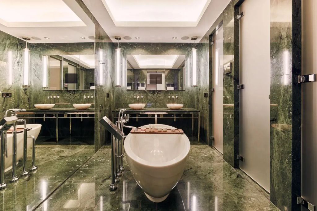 Luxuriöses Badezimmer mit freistehender Badewanne und grünem Marmor