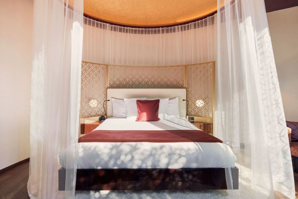 Luxuriöses Doppelbett in einer eleganten Suite mit dekorativen Wänden und weichen Stoffen