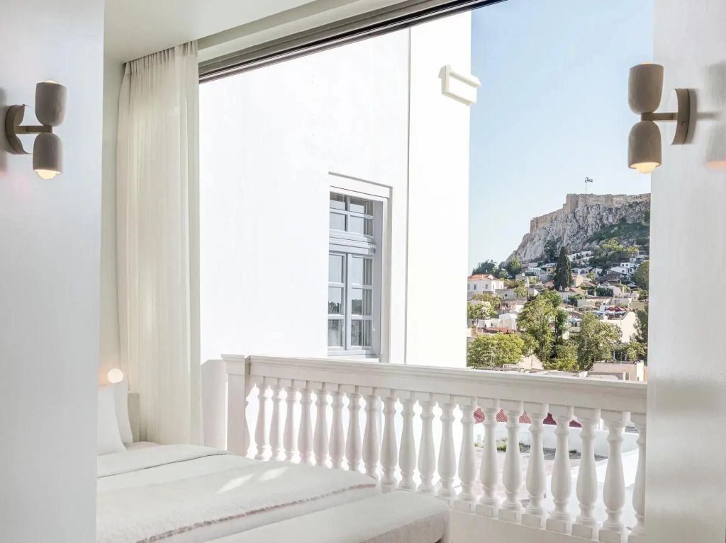 Balkon mit Marmorsäulen und Ausblick auf grüne Umgebung und Akropolis.