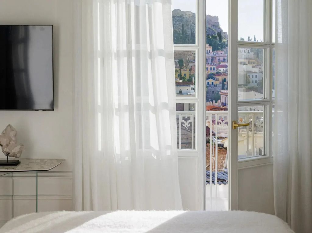Fenster mit Blick auf die Akropolis und hellem Vorhang, Bett im Vordergrund