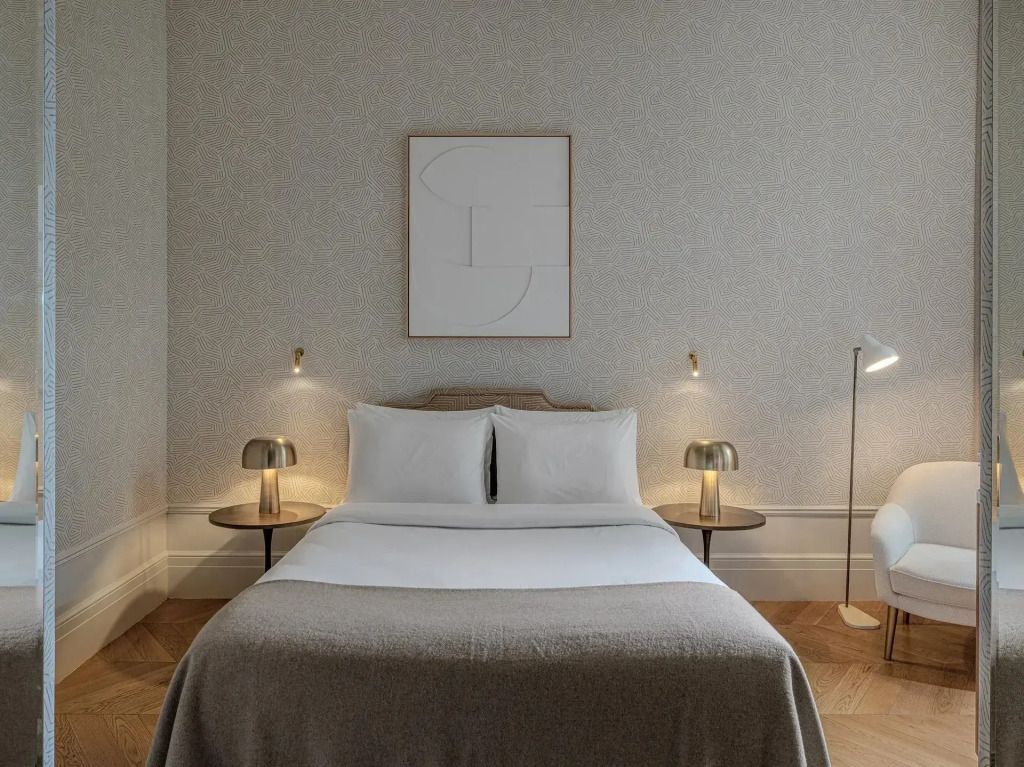 Einzelzimmer mit Doppelbett, kunstvolles Wandbild und seitliche Leselampen.